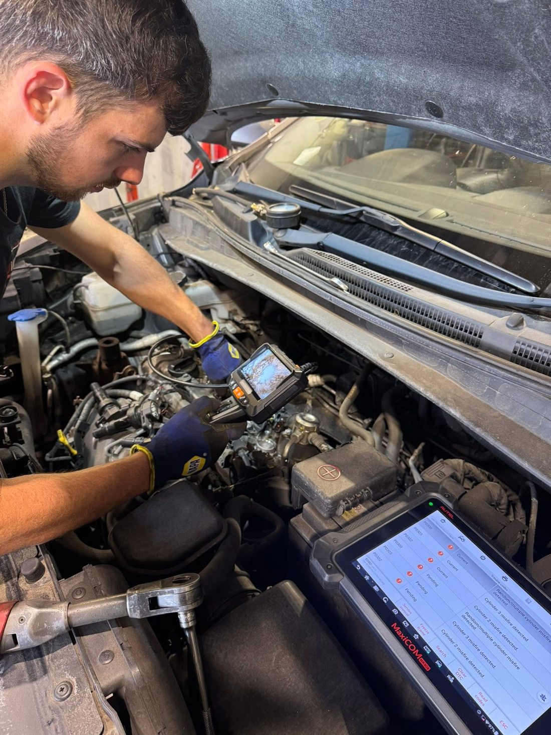Elliot working under the bonnet with diagnostic equipment at Motoworx