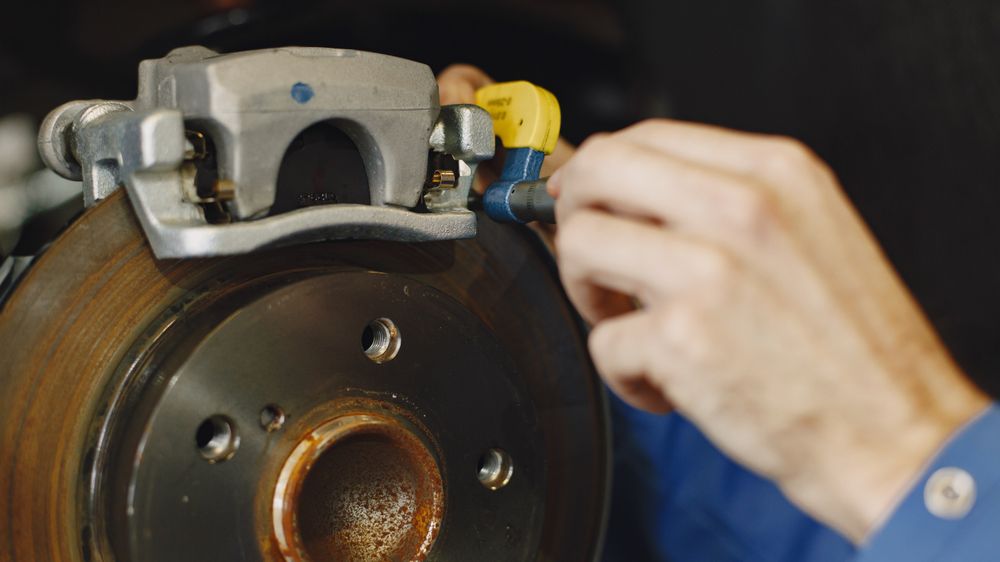 A brake disc and caliper with the wheel removed, being worked on