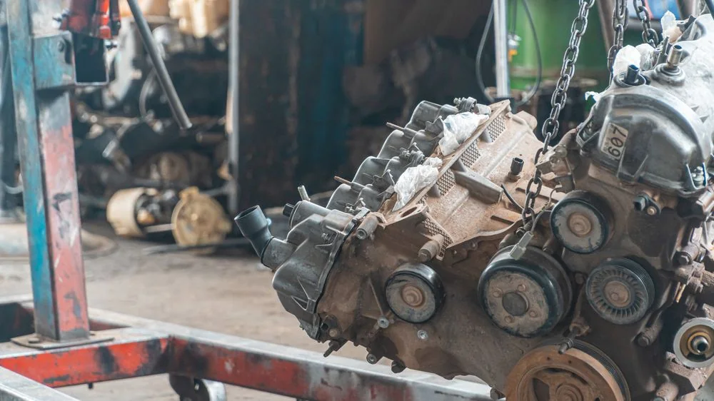 An engine lifted out of a car on a workshop hoist